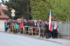 Lampionový průvod - zástup lidí před školou v čele s vlajkou